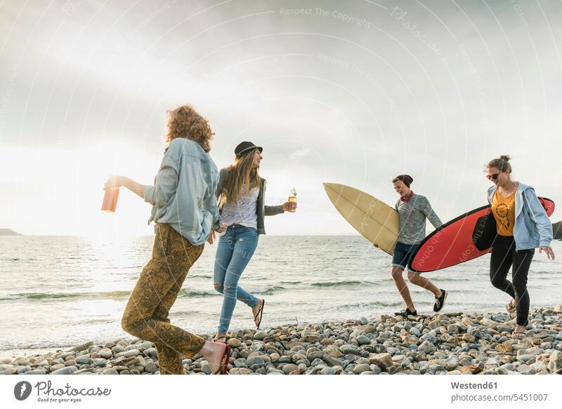 Glückliche Freunde mit Surfbrettern am steinigen Strand glücklich glücklich sein glücklichsein Surfer Wellenreiter Beach Straende Strände Beaches surfboard