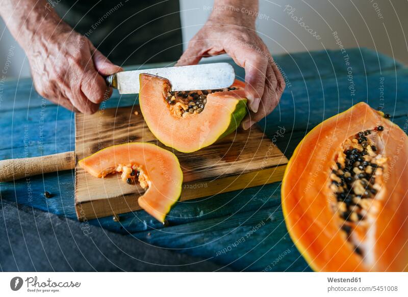Hände eines älteren Mannes beim Papayaschneiden Gesunde Ernährung Ernaehrung Gesunde Ernaehrung Gesundheit gesund Männer männlich Hälfte halbe halbiert halber