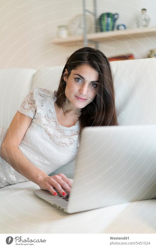 Porträt einer Frau auf Couch mit Laptop Notebook Laptops Notebooks Sofa Couches Liege Sofas weiblich Frauen Computer Rechner Erwachsener erwachsen Mensch