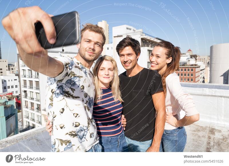 Freunde machen Selfies auf einer Dachterrasse lächeln Dachterrassen fotografieren feiern Kamera Kameras Fotoapparat Fotokamera Freundschaft Kameradschaft