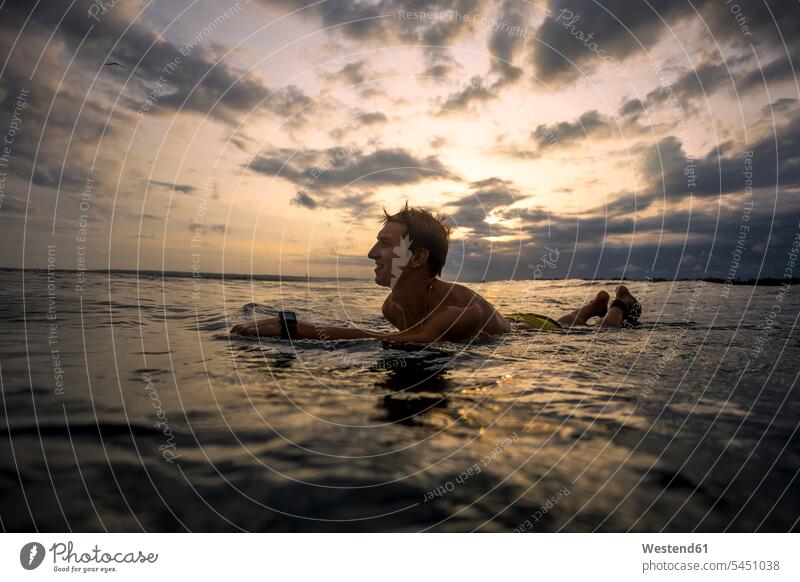 Indonesien, Bali, Surfer bei Sonnenuntergang auf dem Surfbrett liegend Meer Meere Wellenreiter Surfen Surfing Wellenreiten Gewässer Wasser Wassersport Sport