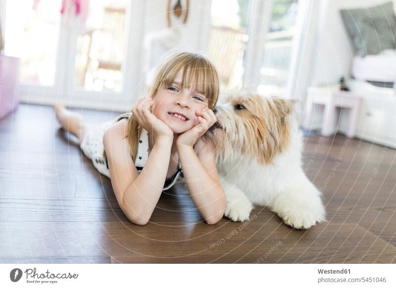 Mädchen mit Hund liegt zu Hause auf dem Boden glücklich Glück glücklich sein glücklichsein weiblich lächeln Hunde liegen liegend Kind Kinder Kids Mensch