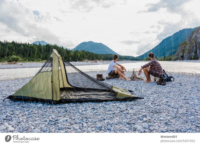 Deutschland, Bayern, zwei Wanderer zelten auf einer Kiesbank und schauen sich die Aussicht an Freunde Freundschaft Kameradschaft Camping Campen Zelt Zelte