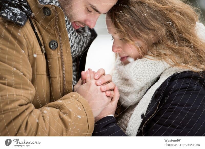 Glückliches junges Paar beim Händchenhalten Winter winterlich Winterzeit Treue treu Pärchen Paare Partnerschaft Hände halten Haendchen halten Hand halten
