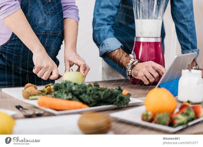Hände eines Paares, das Früchte zubereitet und eine Tablette zur Zubereitung von Smoothies verwendet Pärchen Partnerschaft Mensch Menschen Leute People Personen