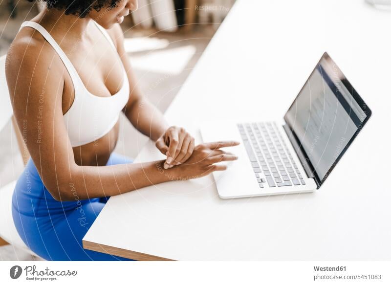 Fitte junge Frau mit Laptop zu Hause arbeiten Arbeit lernen fit sitzen sitzend sitzt Notebook Laptops Notebooks Online weiblich Frauen Training trainieren