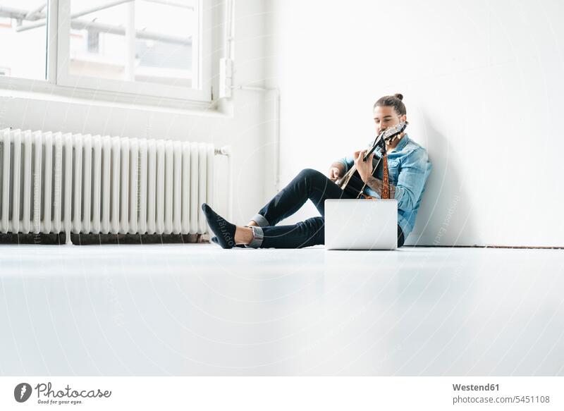 Mann sitzt mit Laptop auf dem Boden und spielt Gitarre Männer männlich Gitarren Notebook Laptops Notebooks Erwachsener erwachsen Mensch Menschen Leute People