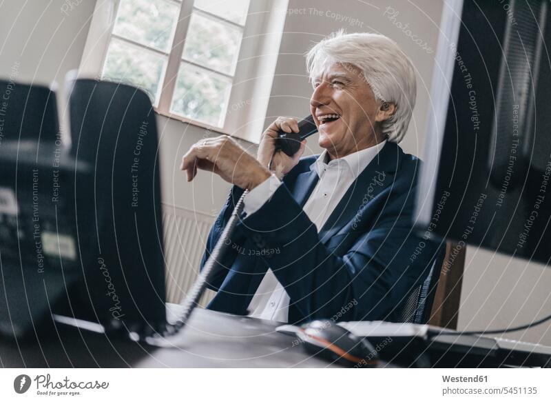 Lachender Senior-Geschäftsmann am Telefon in seinem Büro Businessmann Businessmänner Geschäftsmänner Office Büros telefonieren anrufen Anruf telephonieren
