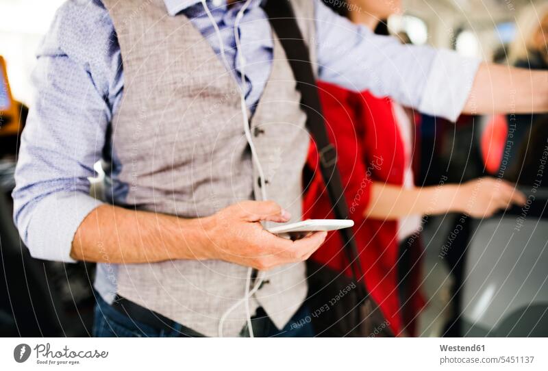 Nahaufnahme eines Geschäftsmannes mit Smartphone in der Straßenbahn Mann Männer männlich Pendler Handy Mobiltelefon Handies Handys Mobiltelefone Erwachsener