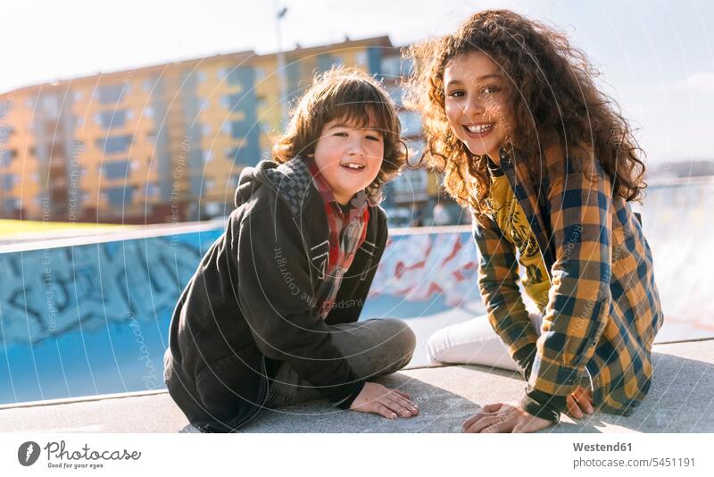 Porträt von zwei Kindern, die an einer Wand sitzen Portrait Porträts Portraits Freunde Freundschaft Kameradschaft Skatepark Skateboardpark Skateboard-Park