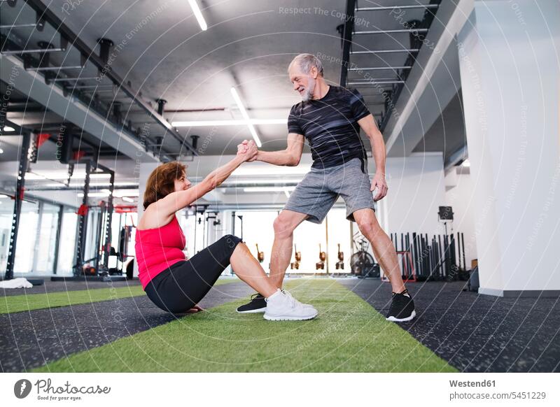 Älterer Mann unterstützt Ehefrau im Fitnessstudio Gymnastik trainieren Senioren alte ältere Fitnessclubs Fitnessstudios Turnhalle Paar Pärchen Paare