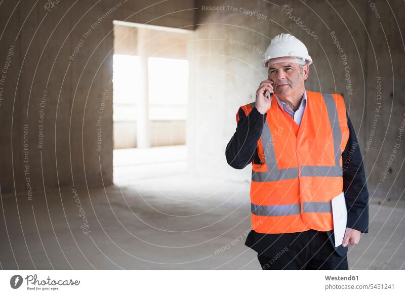 Mann am Telefon mit Sicherheitsweste in einem im Bau befindlichen Gebäude Handy Mobiltelefon Handies Handys Mobiltelefone Architekt Architekten Männer männlich