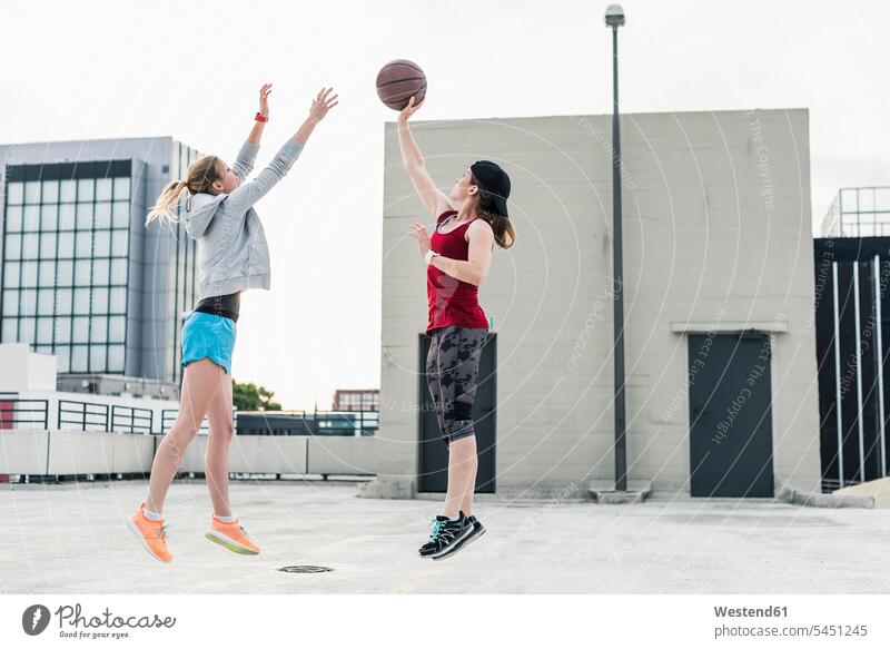Zwei Frauen spielen Basketball auf einem Parkdeck in der Stadt weiblich Freundinnen Basketbaelle Basketbälle Erwachsener erwachsen Mensch Menschen Leute People