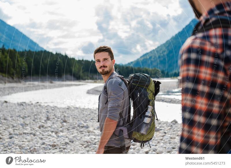 Deutschland, Bayern, Porträt eines jungen Wanderers mit Rucksack, der seinen Freund anschaut Portrait Porträts Portraits Freunde Freundschaft Kameradschaft