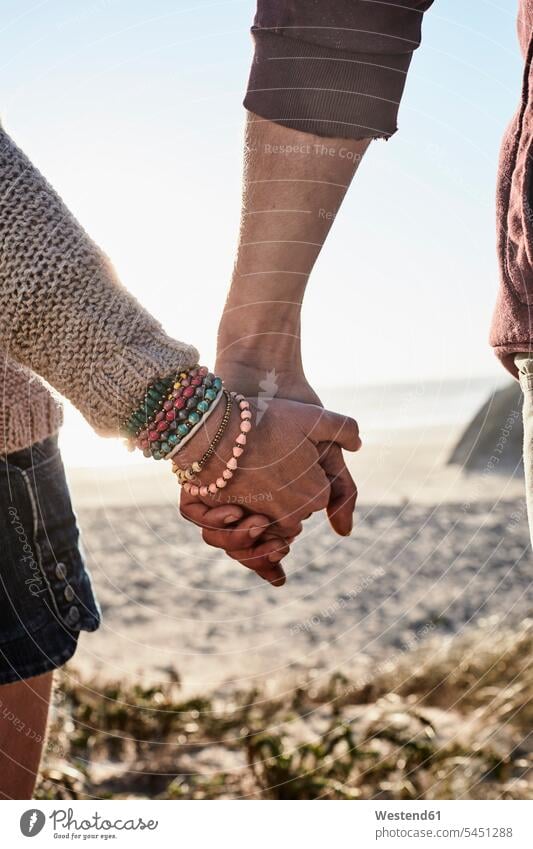 Portugal, Algarve, Nahaufnahme eines Paares, das sich bei Sonnenuntergang am Strand an den Händen hält Hand Pärchen Partnerschaft Beach Straende Strände Beaches