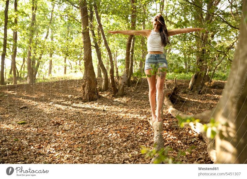 Junge Frau im Wald beim Balancieren auf einem Baumstamm Bäume Baeume Forst Wälder balancieren Balance weiblich Frauen ausgeglichen Ausgeglichenheit