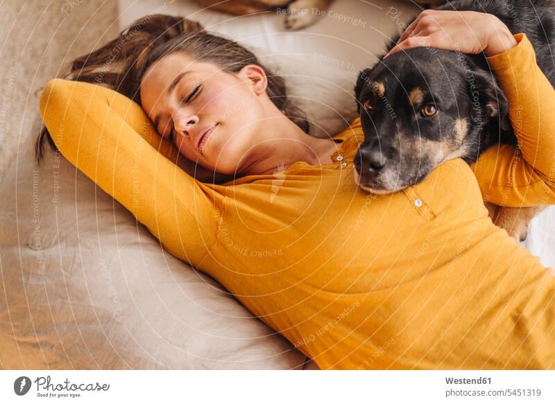 Frau liegt mit ihrem Hund im Bett schlafen schlafend Hunde kuscheln schmusen knuddeln umarmen Umarmung Umarmungen Arm umlegen weiblich Frauen Betten liegen