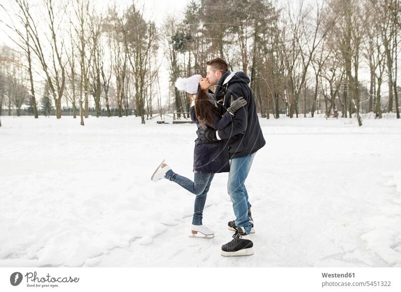 Paar, das auf einem zugefrorenen See Schlittschuh läuft, sich küsst und umarmt küssen Küsse Kuss aktiv vereist eingefroren Pärchen Paare Partnerschaft