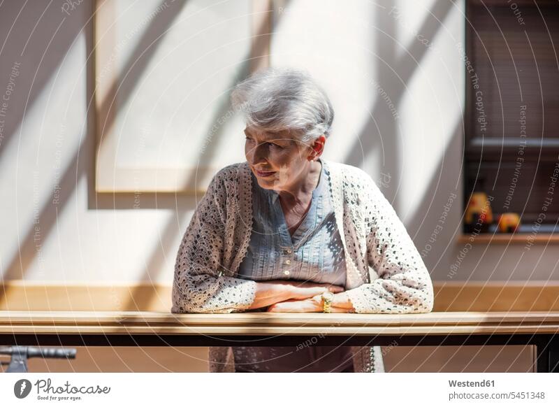Einsame ältere Frau lehnt am Geländer und schaut nach unten aufstützen aufgestuetzt aufgestützt Seniorin Seniorinnen alt beobachten zuschauen ansehen traurig