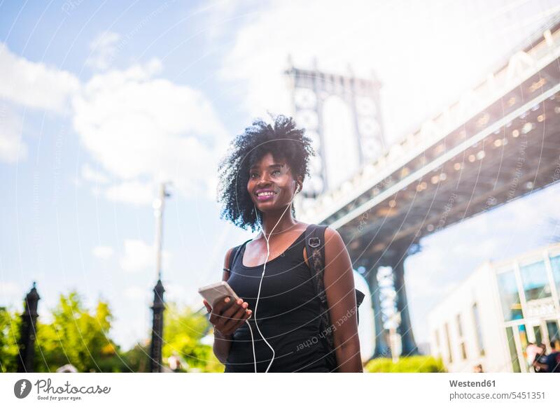 USA, New York City, Brooklyn, lächelnde Frau beim Musikhören an der Manhattan Bridge weiblich Frauen hoeren Erwachsener erwachsen Mensch Menschen Leute People