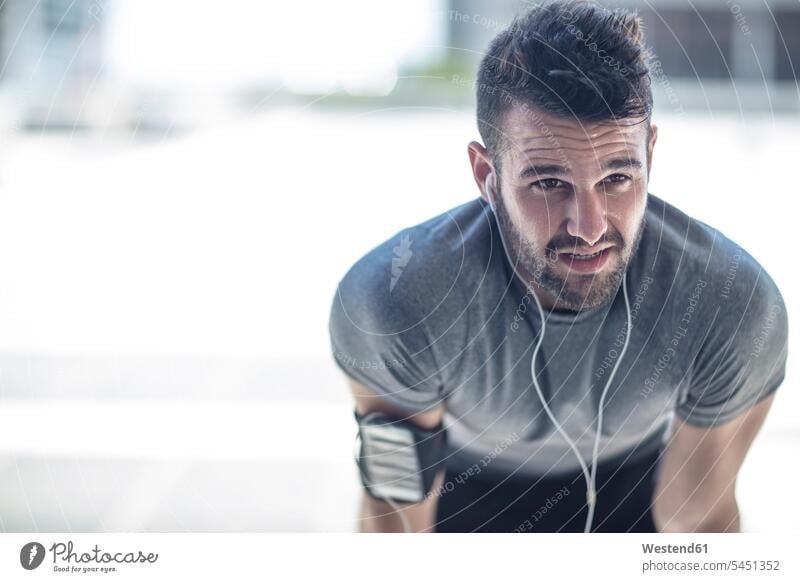 Erschöpfter Sportler bei einer Pause in der Stadt trainieren Ohrhörer Mann Männer männlich In-Ear Kopfhörer Kopfhoerer Erwachsener erwachsen Mensch Menschen