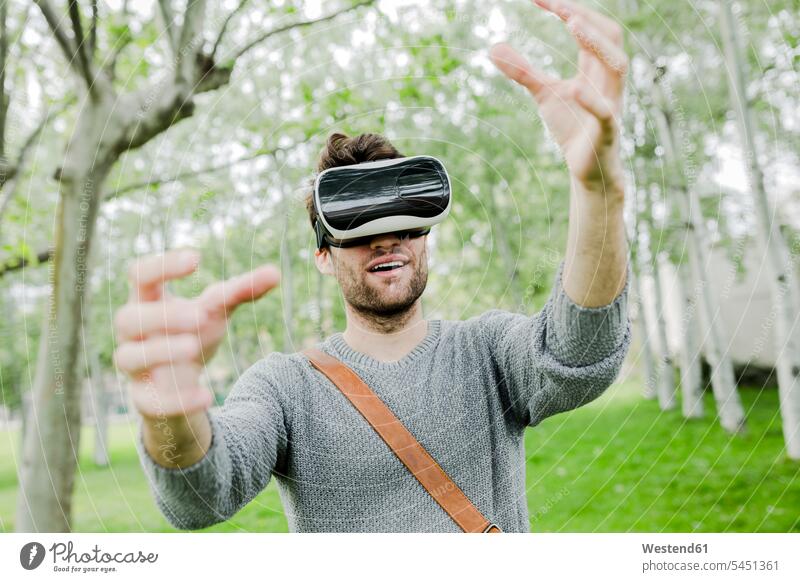 Mann trägt in der Natur eine Virtual-Reality-Brille und benutzt seine Hände Virtual Reality Brille Virtual Reality-Brille VR Brille Männer männlich Wearable