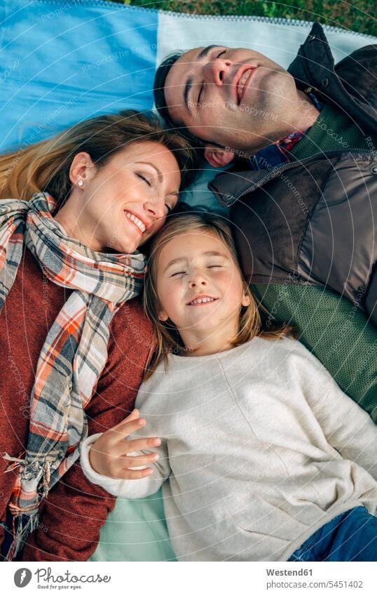 Glückliche Familie liegt mit geschlossenen Augen auf einer Decke liegen liegend Decken glücklich glücklich sein glücklichsein lächeln entspannt entspanntheit