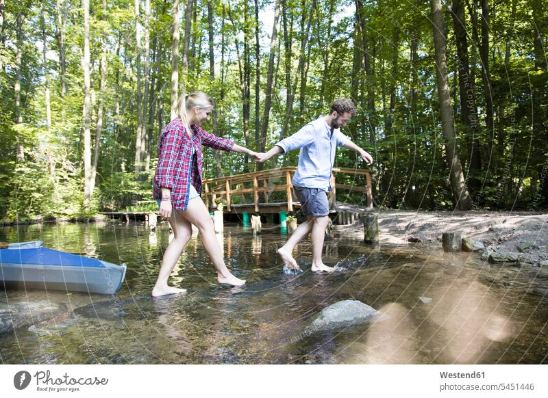 Junges Paar überquert einen Waldbach überqueren Pärchen Paare Partnerschaft Forst Wälder Bach Bäche Baeche Mensch Menschen Leute People Personen Gewässer Wasser
