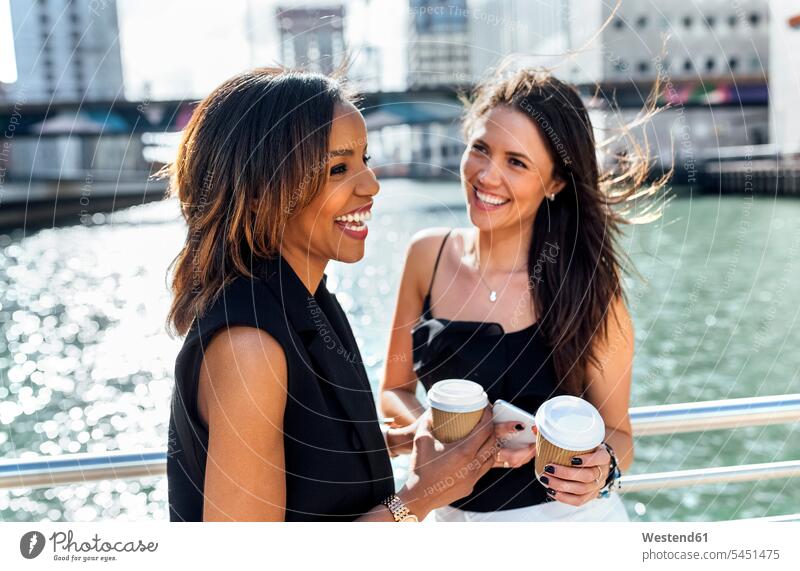 Zwei glückliche Frauen bei einer Kaffeepause auf einer Brücke in der Stadt weiblich Kollegin Kolleginnen lachen Getränk Getraenk Getränke Getraenke