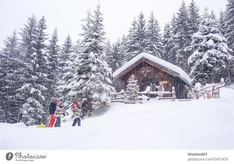 Österreich, Altenmarkt-Zauchensee, Familie mit Schlitten am Holzhaus zur Weihnachtszeit Winter winterlich Winterzeit Schnee Weihnachten Christmas X-Mas X mas