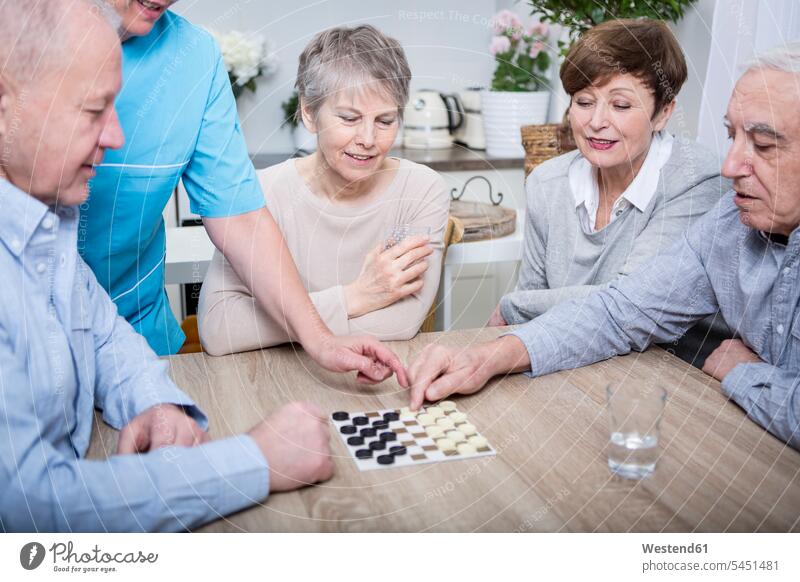 Krankenschwester hilft bei einem Spieleabend für ältere Menschen Altenpflegerin Altenpflegerinnen Pflegerin Pflegerinnen spielen glücklich Glück glücklich sein