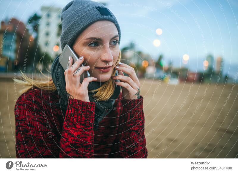 Junge Frau im Winter mit dem Handy am Strand telefonieren anrufen Anruf telephonieren Beach Straende Strände Beaches weiblich Frauen Telefon benutzen