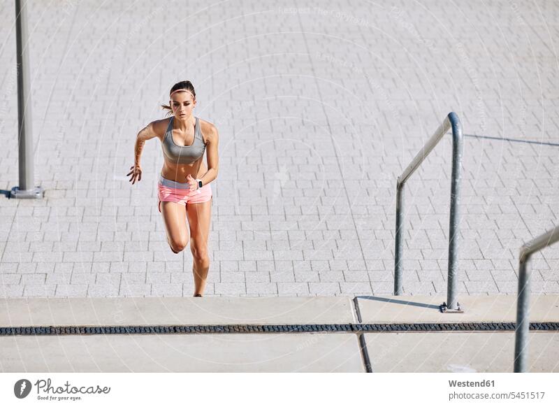Fitte junge Frau, die auf einer Treppe läuft trainieren Treppenaufgang weiblich Frauen fit laufen rennen Erwachsener erwachsen Mensch Menschen Leute People