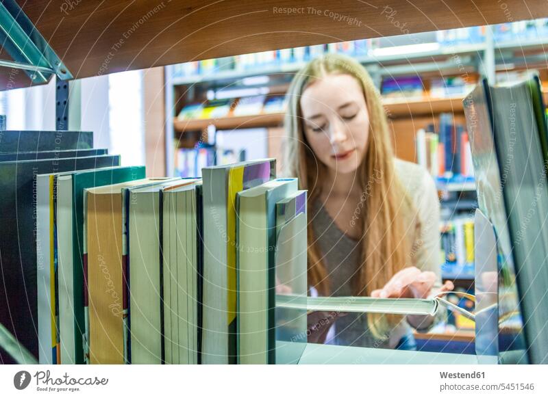 Teenagermädchen hinter einem Bücherregal in einer öffentlichen Bibliothek Buch Teenagerin junges Mädchen Teenagerinnen weiblich junge Frau Leser lesen Lektüre