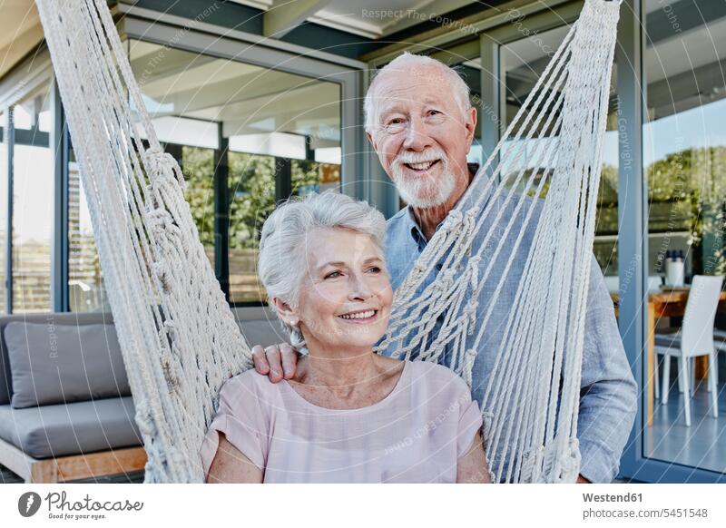 Älteres Ehepaar auf Terrasse, Frau sitzt in Hängematte Paar Pärchen Paare Partnerschaft Älter werden Aelter werden Altern sitzen sitzend Gemeinsam Zusammen