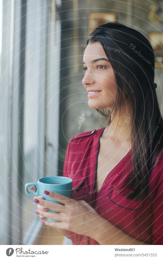 Frau trinkt Tee und schaut durchs Fenster weiblich Frauen schauen sehend trinken Portrait Porträts Portraits Teetasse Teetassen lächeln Erwachsener erwachsen