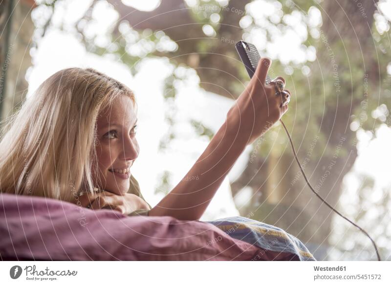 Lächelnde junge Frau liegt auf dem Bett und macht ein Selfie mit ihrem Handy weiblich Frauen Smartphone iPhone Smartphones Selfies Erwachsener erwachsen Mensch