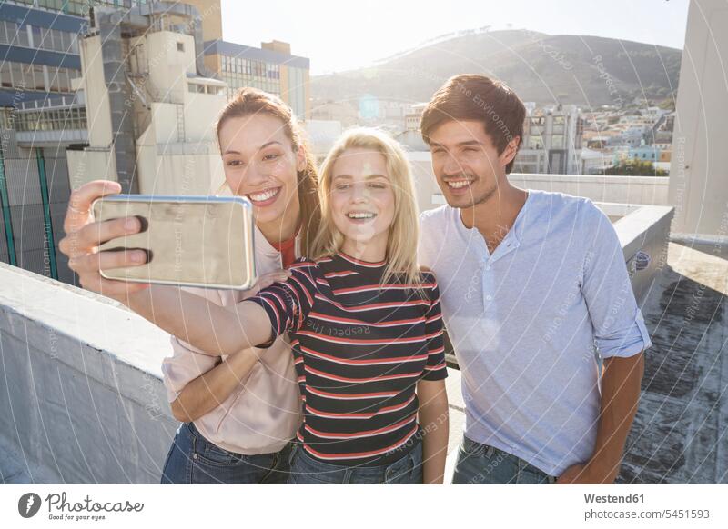 Freunde machen Selfies auf einer Dachterrasse Kamera Kameras fotografieren feiern Dachterrassen lächeln Fotoapparat Fotokamera Freundschaft Kameradschaft Spaß