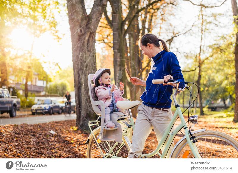 Mutter und Tochter fahren Fahrrad, das Baby trägt einen Helm und sitzt im Kindersitz Bikes Fahrräder Räder Rad spielen radfahren fahrradfahren radeln