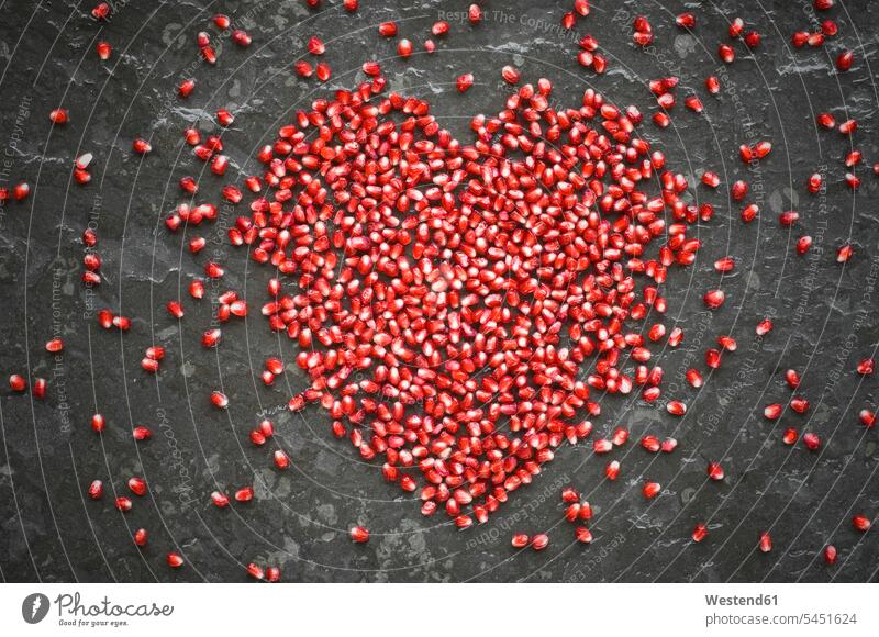 Herzform von Granatapfelkernen auf Schiefer Food and Drink Lebensmittel Essen und Trinken Nahrungsmittel Symbolbild Symbolik Textfreiraum Liebesherzen