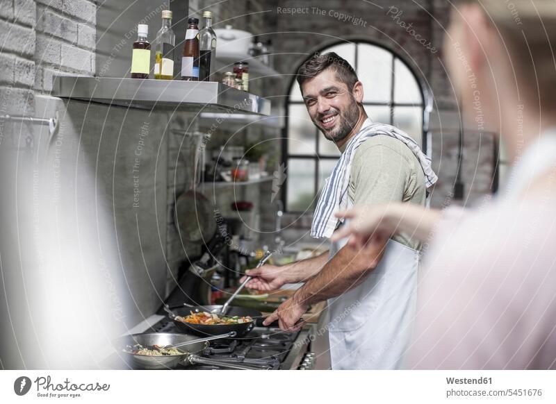 Lächelnder Mann bereitet Essen vor und sieht seine Frau an kochen Paar Pärchen Paare Partnerschaft lächeln Mensch Menschen Leute People Personen Europäer