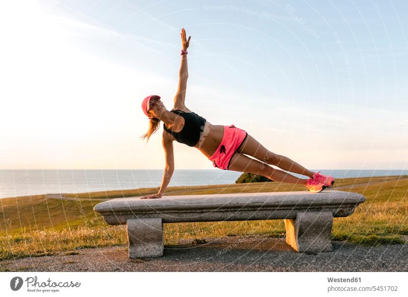 Junge Frau beim Krafttraining auf einer Bank am Meer fit trainieren aufwärmen sich aufwärmen sich aufwaermen weiblich Frauen Side-Plank Seitenstütz