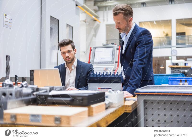 Zwei Männer am Tisch in der Fabrik mit Laptop Kollegen Arbeitskollegen Fabriken Notebook Laptops Notebooks Geschäftsmann Businessmann Businessmänner