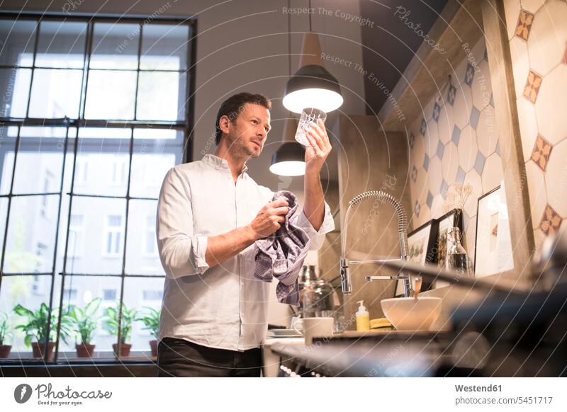 Mann in der Küche trocknet Glas mit Handtuch Männer männlich Küchen Erwachsener erwachsen Mensch Menschen Leute People Personen abtrocknen stehen stehend steht