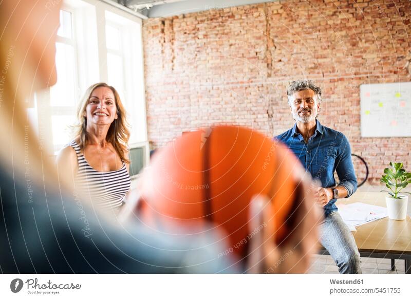 Lächelnde Kollegen mit Basketball im Amt lächeln Büro Office Büros Arbeitskollegen Sport Arbeitsplatz Arbeitsstätte Arbeitstelle modern spielen Ausschnitt Teil