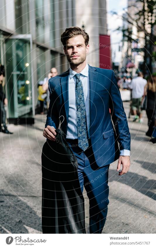 Gutaussehender Geschäftsmann geht in Manhattan spazieren, trägt Jacke auf einem Kleiderbügel Jacken gehen gehend Businessmann Businessmänner Geschäftsmänner
