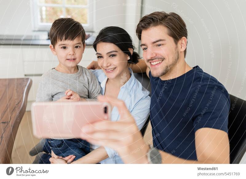 Glückliche Familie macht ein Selfie zu Hause Familien Handy Mobiltelefon Handies Handys Mobiltelefone lächeln Selfies Mensch Menschen Leute People Personen