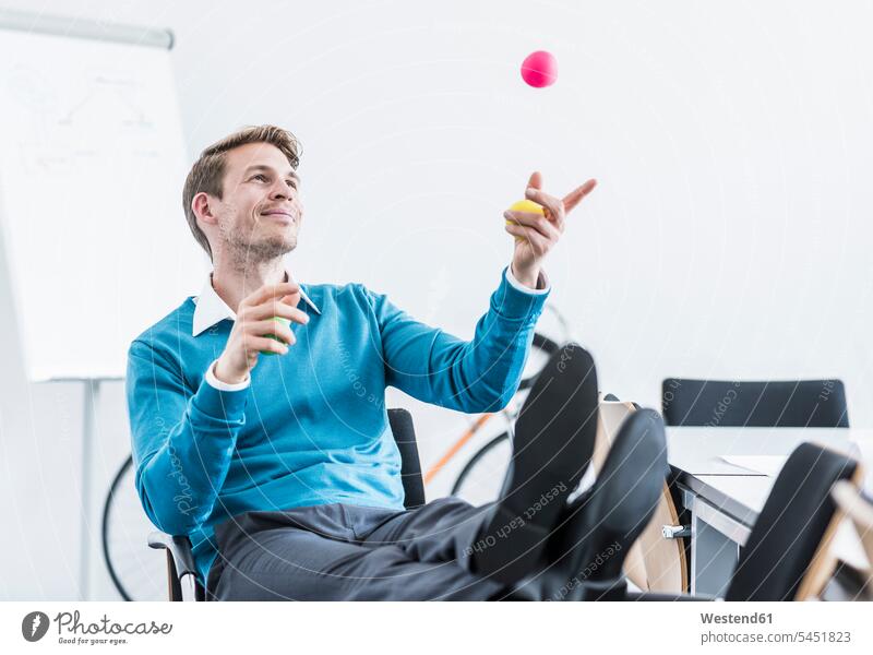 Lächelnder Geschäftsmann jongliert im Büro mit Bällen Businessmann Businessmänner Geschäftsmänner lächeln Ball jonglieren Office Büros Geschäftsleute