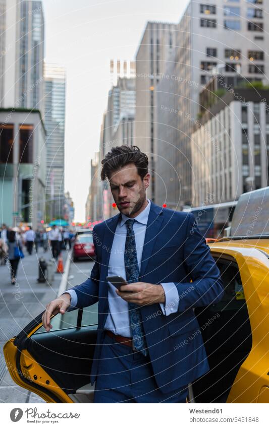 Geschäftsmann verlässt gelbes Taxi in Manhattan attraktiv schoen gut aussehend schön Attraktivität gutaussehend hübsch Handy Mobiltelefon Handies Handys