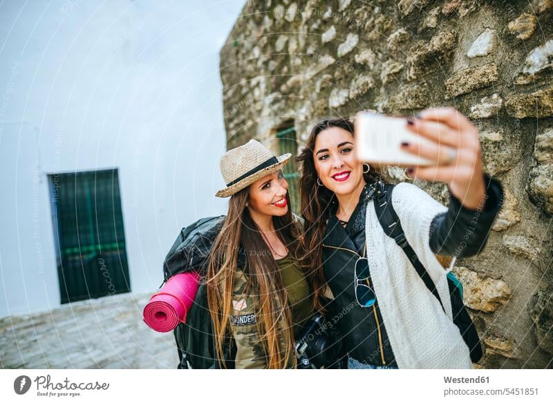 Zwei glückliche junge Frauen machen ein Selfie mit einem Smartphone Handy Mobiltelefon Handies Handys Mobiltelefone Selfies fotografieren Freundinnen lächeln